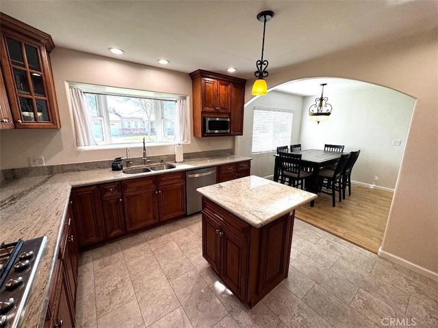 kitchen featuring pendant lighting, appliances with stainless steel finishes, light stone countertops, and sink