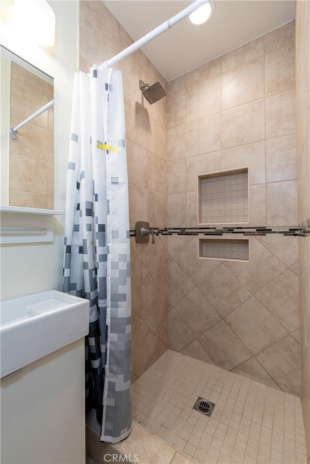 bathroom featuring a tile shower and vanity