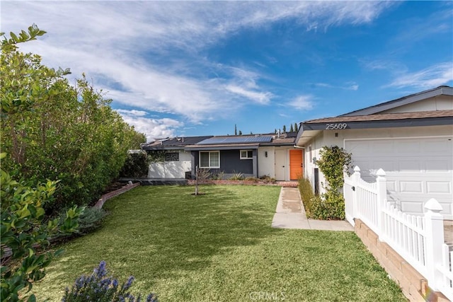 ranch-style home with a garage, a front lawn, and solar panels