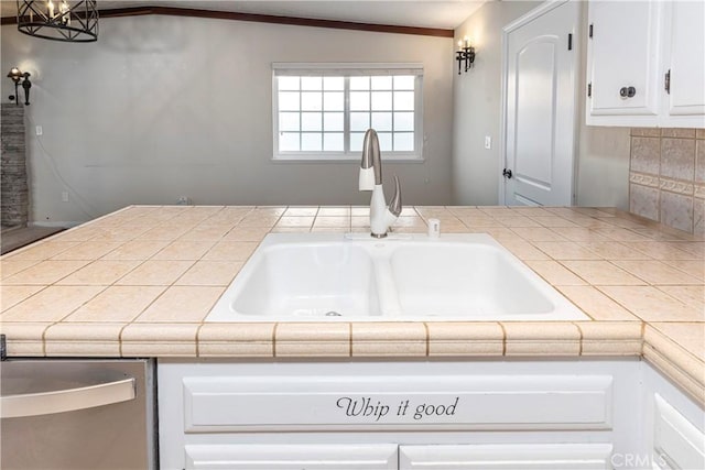 kitchen featuring tasteful backsplash, a sink, tile counters, and white cabinets