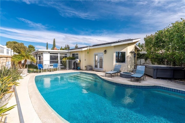 view of pool with french doors, fence, a fenced in pool, and a hot tub