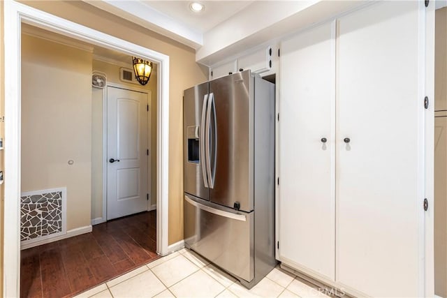 kitchen with visible vents, baseboards, white cabinetry, light wood-type flooring, and stainless steel fridge with ice dispenser