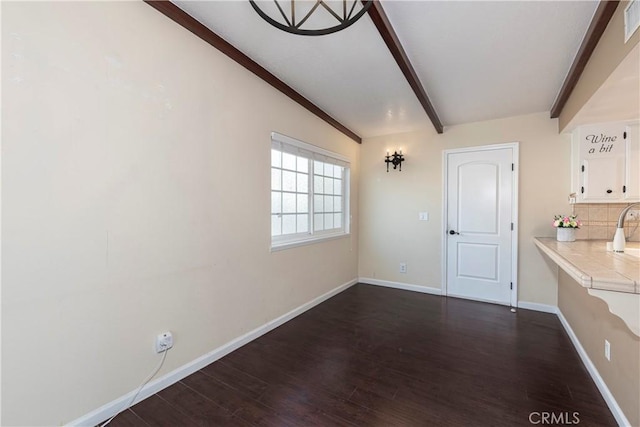 unfurnished dining area featuring visible vents, baseboards, dark wood finished floors, and beamed ceiling