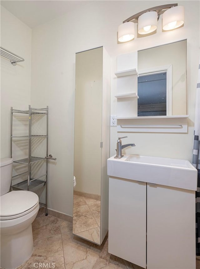 bathroom featuring vanity, toilet, and baseboards