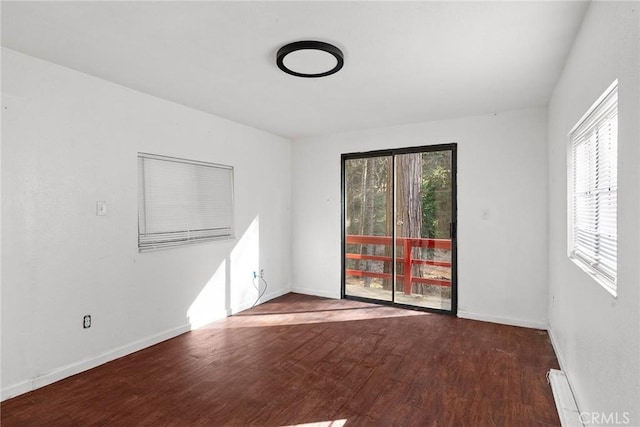 empty room with hardwood / wood-style flooring, a baseboard heating unit, and a wealth of natural light