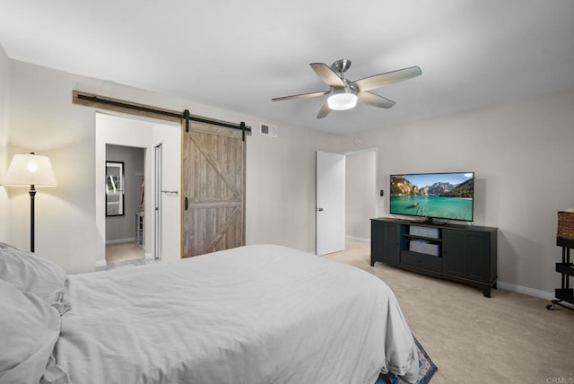 bedroom with ceiling fan, a barn door, light carpet, visible vents, and baseboards