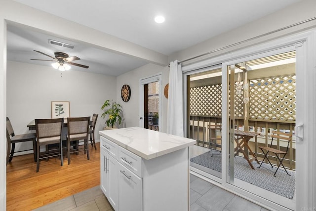 kitchen with light wood-type flooring, a wealth of natural light, white cabinetry, and visible vents