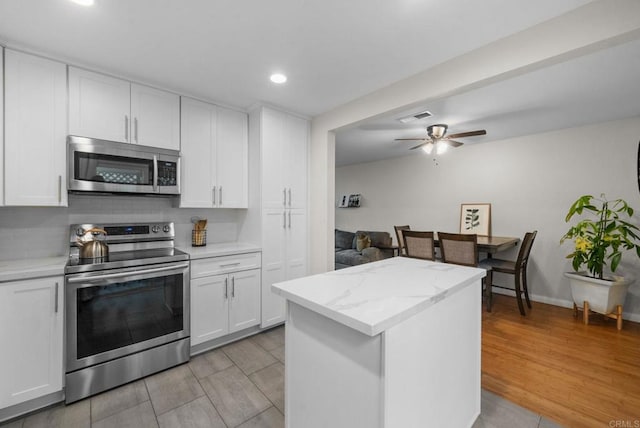 kitchen with stainless steel appliances, visible vents, decorative backsplash, white cabinets, and light wood-type flooring