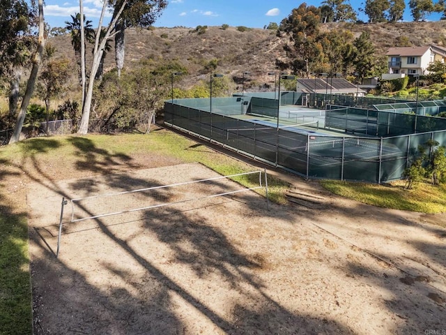 view of tennis court with fence and a mountain view