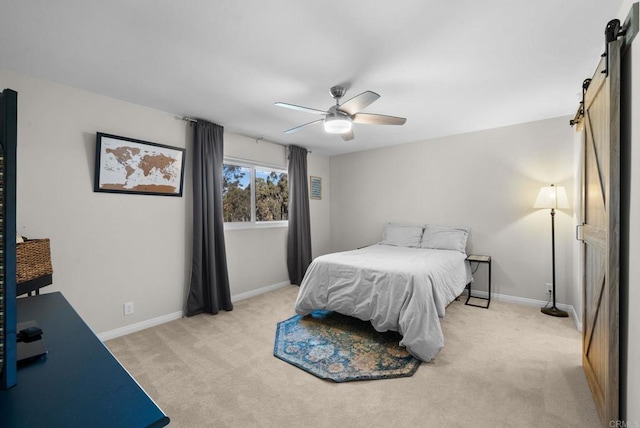 bedroom featuring light colored carpet, ceiling fan, baseboards, and a barn door