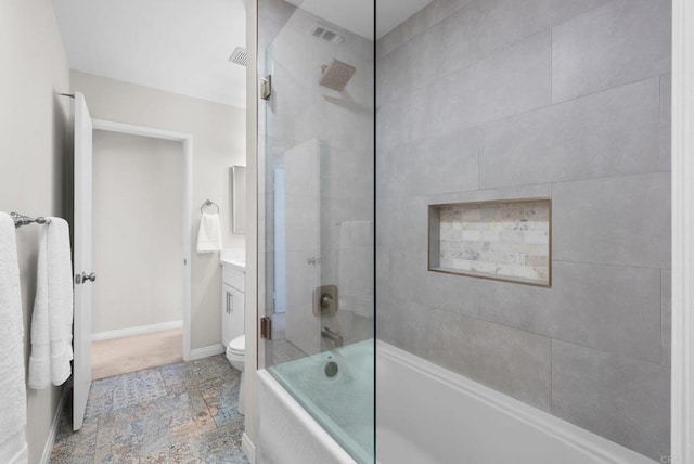 full bath featuring toilet, bath / shower combo with glass door, visible vents, vanity, and baseboards