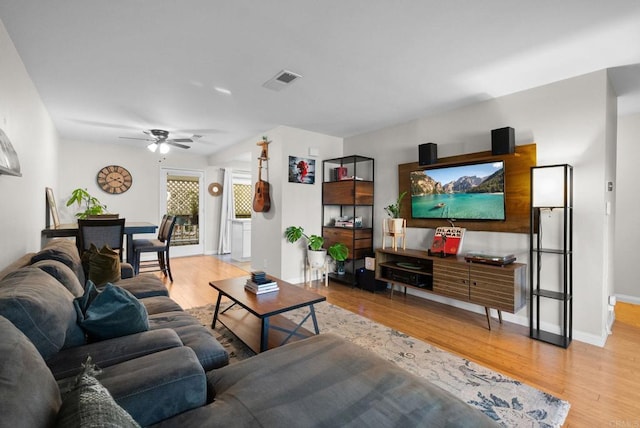 living area with light wood finished floors, a ceiling fan, visible vents, and baseboards