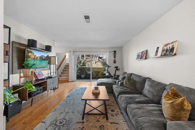 living room with visible vents, stairway, and light wood finished floors