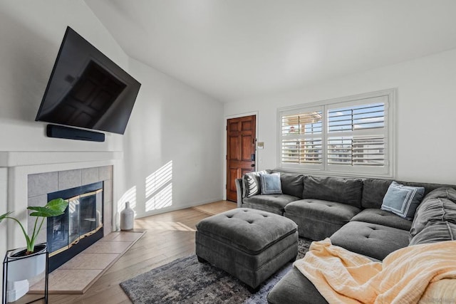 living room with a tiled fireplace and light hardwood / wood-style floors