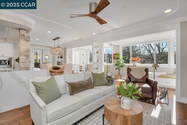 living room featuring decorative columns, plenty of natural light, and ceiling fan with notable chandelier