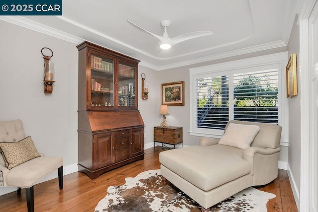 sitting room with hardwood / wood-style flooring, ceiling fan, and ornamental molding