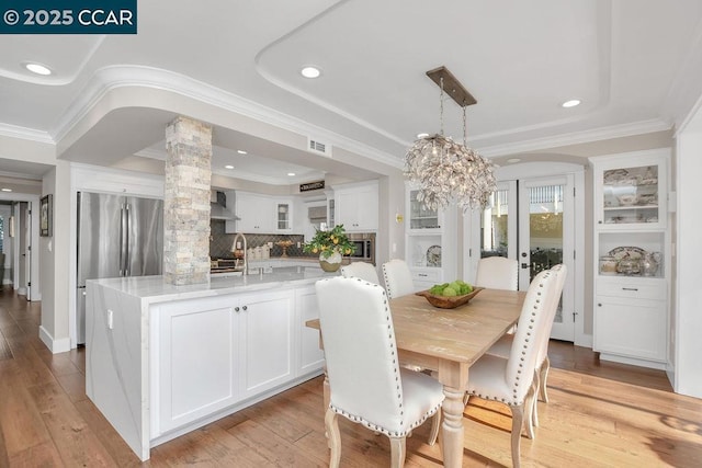 dining room with ornate columns, crown molding, and light hardwood / wood-style floors