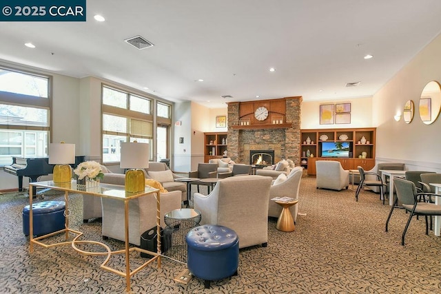 carpeted living room with a stone fireplace