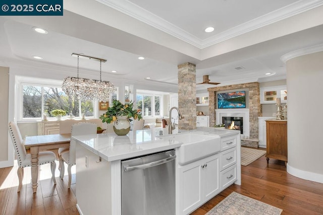 kitchen featuring decorative light fixtures, white cabinetry, an island with sink, stainless steel dishwasher, and crown molding