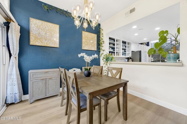 dining space with an inviting chandelier and light hardwood / wood-style flooring