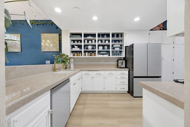 kitchen with sink, appliances with stainless steel finishes, light hardwood / wood-style floors, white cabinets, and decorative backsplash