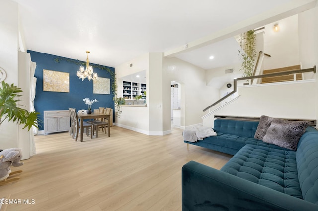 living room featuring an inviting chandelier, light hardwood / wood-style flooring, and beamed ceiling