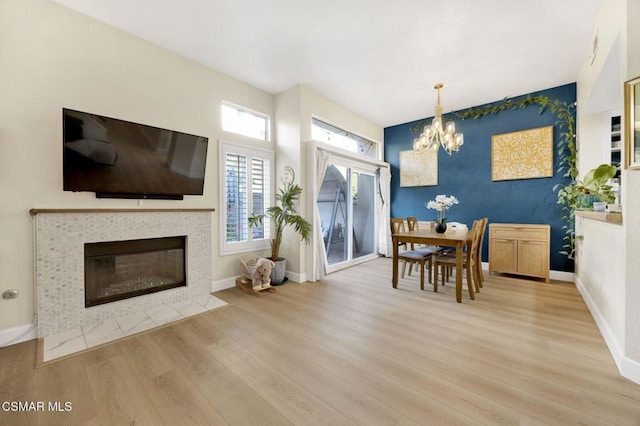 interior space with a notable chandelier, light hardwood / wood-style floors, and a tile fireplace