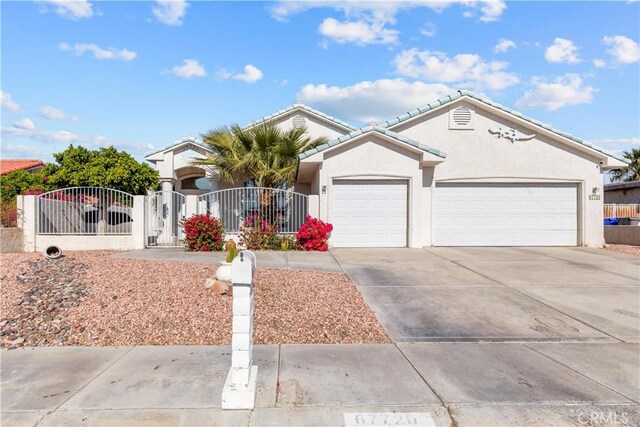 single story home featuring a garage, a gate, concrete driveway, and stucco siding