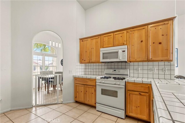 kitchen featuring white appliances, a sink, tile countertops, and decorative backsplash