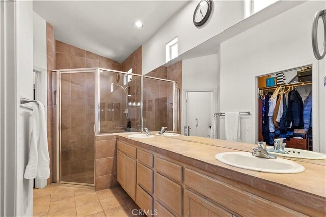 bathroom featuring lofted ceiling, a sink, a shower stall, and tile patterned floors