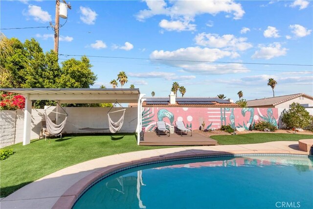 exterior space with a deck, a yard, fence, and a fenced in pool