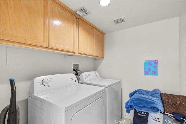 clothes washing area with visible vents, cabinet space, and separate washer and dryer