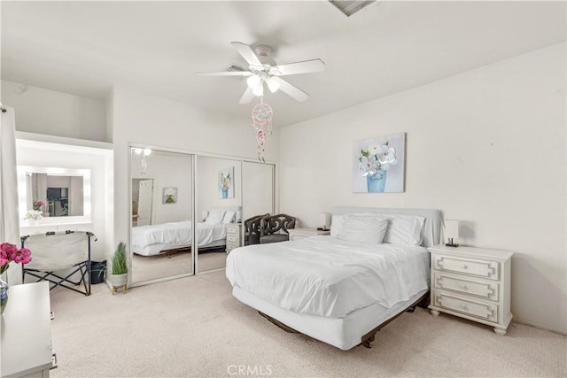 bedroom with ceiling fan, light carpet, and a closet