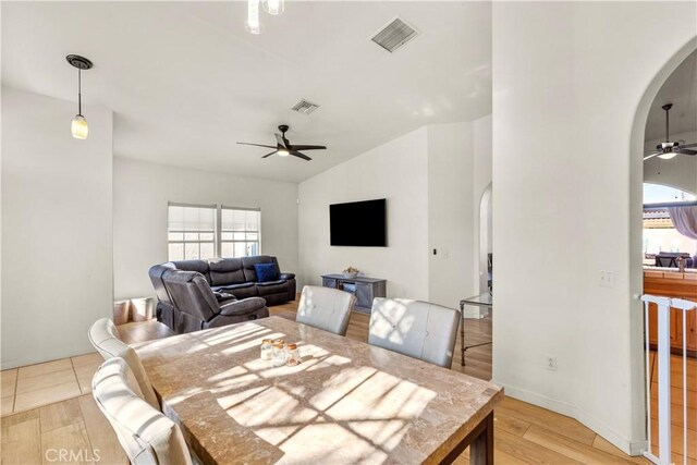 dining space with light wood-type flooring, arched walkways, visible vents, and ceiling fan