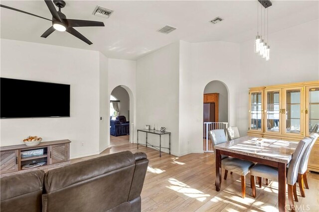 living room with visible vents, arched walkways, and light wood-style flooring