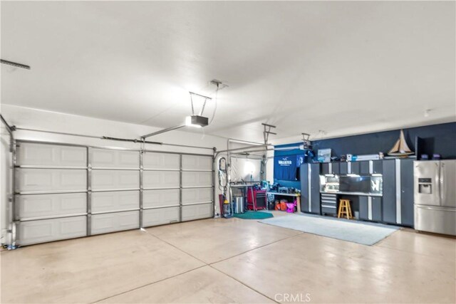 garage featuring a garage door opener and stainless steel fridge with ice dispenser