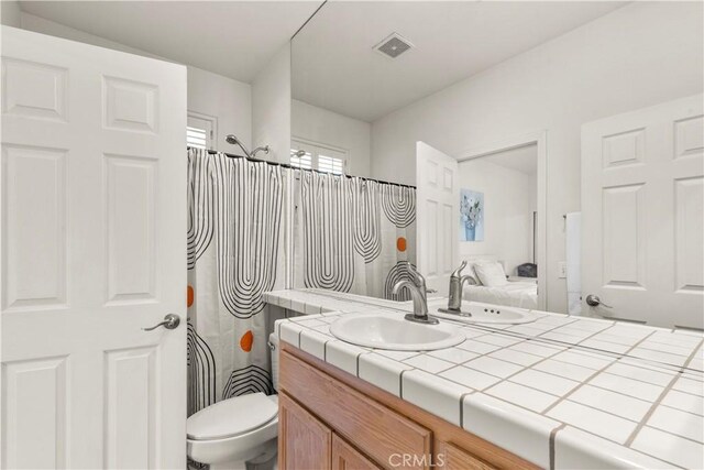 bathroom featuring a shower with curtain, visible vents, vanity, and toilet