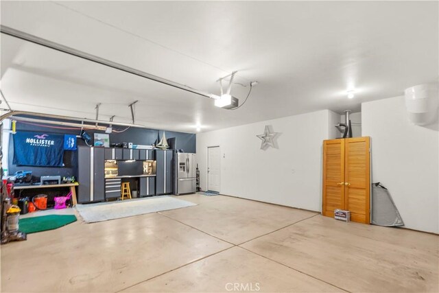 garage featuring a garage door opener and stainless steel fridge with ice dispenser