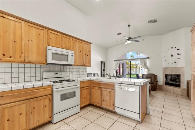 kitchen featuring white appliances, a tile fireplace, tasteful backsplash, tile countertops, and kitchen peninsula