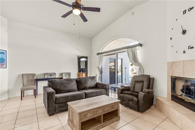 tiled living room featuring a tiled fireplace, ceiling fan, and high vaulted ceiling