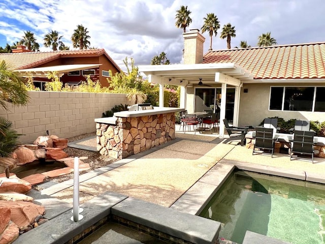 back of house featuring a patio, exterior bar, exterior kitchen, ceiling fan, and a fenced in pool