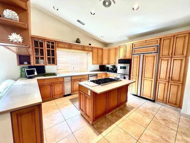 kitchen featuring light tile patterned flooring, lofted ceiling, sink, a kitchen island, and stainless steel appliances