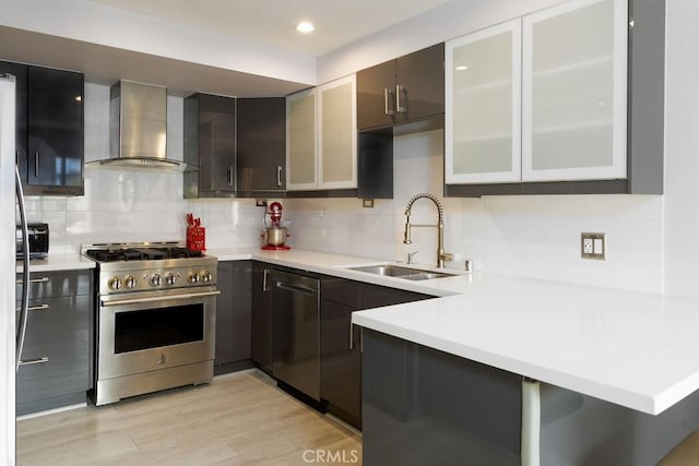 kitchen with sink, stainless steel range, backsplash, and wall chimney exhaust hood