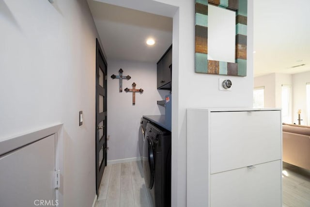 clothes washing area with cabinets, separate washer and dryer, and light wood-type flooring