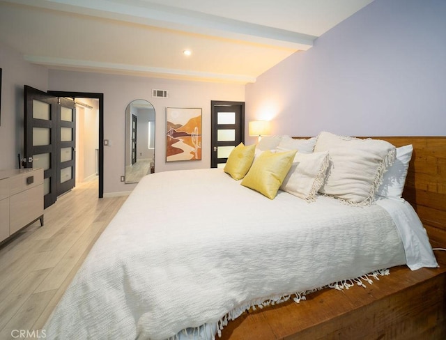 bedroom with beam ceiling and light wood-type flooring