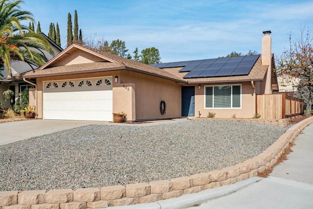 ranch-style home featuring a garage and solar panels