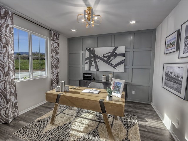 office area with dark wood-type flooring and an inviting chandelier