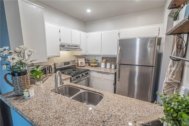 kitchen featuring stainless steel appliances, light stone countertops, sink, and kitchen peninsula