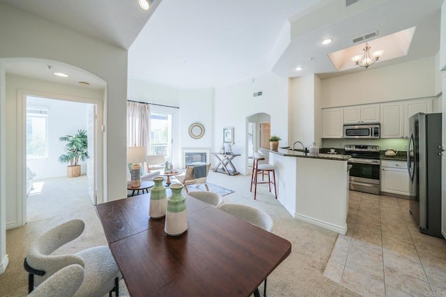 dining space featuring sink, light carpet, and a notable chandelier