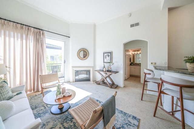 living room featuring a high ceiling, ornamental molding, and light carpet